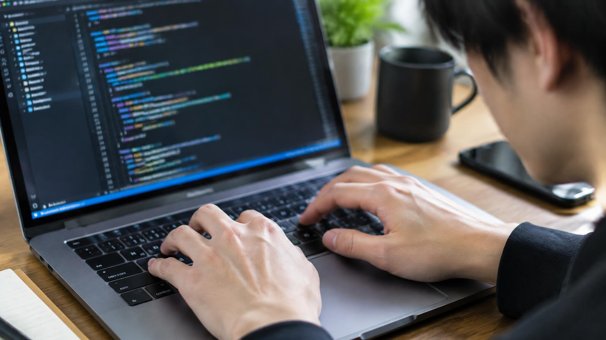 Close-up of hands typing code on a laptop keyboard